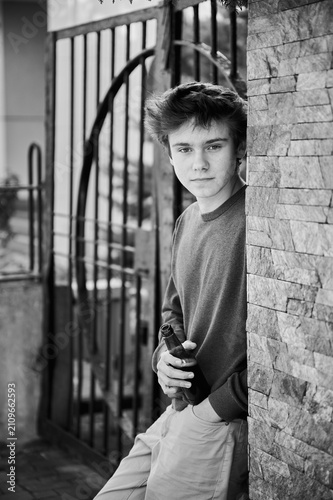 фотографія Young guy holds bottle while standing by stone wall outdoors