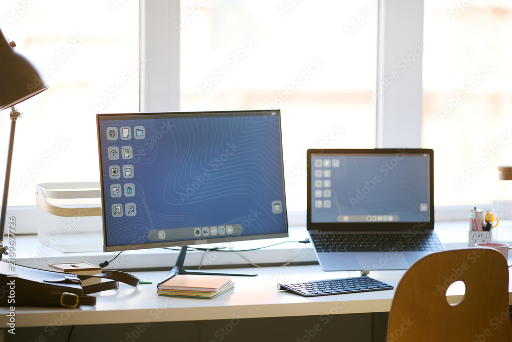 Fototapeta premium Home office workstation displaying desktop monitor and laptop, supporting multitasking and digital productivity. Ideal for remote work, hybrid work, tech setup, wide shot