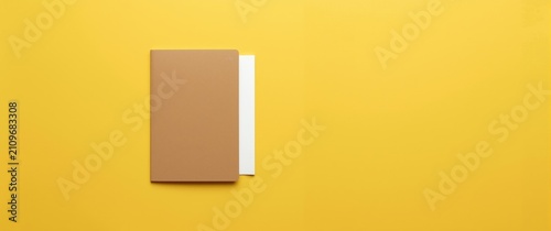 Canvastavla Brown Notebook with White Pages on a Bright Yellow Background