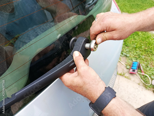 Canvas Print A close-up shot shows a man's hands attaching a car's rear windshield wiper