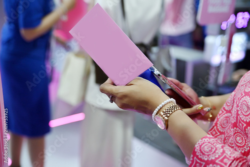 Foto close-up shot of a woman holding a pink card and a smartphone, wearing a watch a