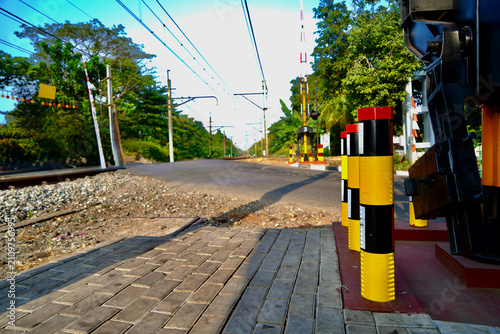 Foto Railway Crossing Barrier Post
Close-up view of a striped yellow, red, and black railway crossing barrier post outdoors, symbolizing public safety, transport infrastructure, and caution