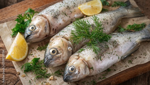 Fresh Whole Fish Garnished with Lemon Slices and Herbs on Wooden Board