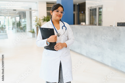 Foto Indian female doctor holding clipboard in clinic lobby