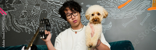 Fotografie Young Asian man balances music and playtime with his dog in vibrant recording st