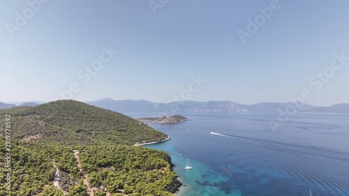Sunny Mid‑morning Drone Flight Over Agistri Panning from Sky to Turquoise Bay with Yachts, Road and Islands in the Distance