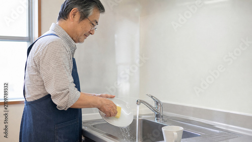 Plakat w ramie 自宅のキッチンで食器を洗う日本人シニア男性