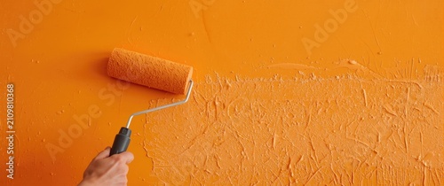 Hand Rolling Paint on a Freshly Coated Orange Wall in a Bright Setting