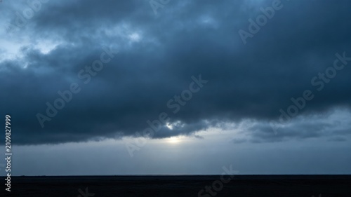 Heavy, overcast sky at dusk with thick gray clouds blocking the sun.