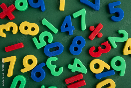 Obraz na plátne Colorful plastic numbers and mathematical symbols on green background