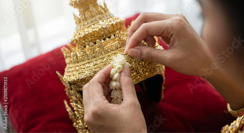 Close up of woman hands decorating traditional thai headdress with fresh jasmine flower garland
