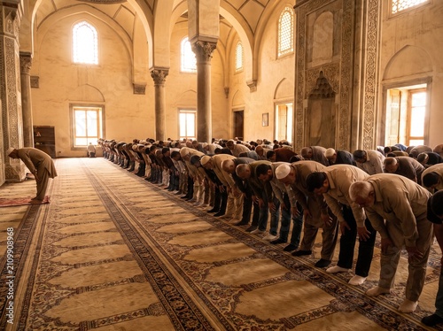 A row of men bow together in jamaat prayer inside a beautiful mosque — congregational worship as visual unity. Ideal for Islamic content, mosque campaigns, Muslim lifestyle, and editorial.