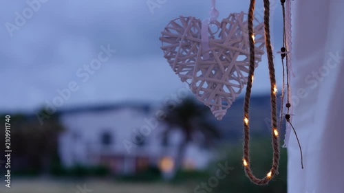 Romantic wicker heart decoration hanging with fairy lights at dusk