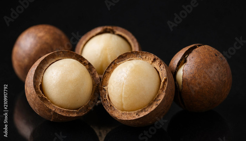 Bild auf Leinwand Several whole macadamia nuts and two halved nuts showing the creamy white interi