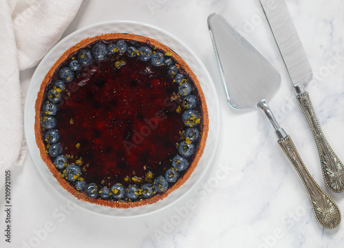 Homemade shortbread pie with blueberries in a white plate on a marble background. Top view