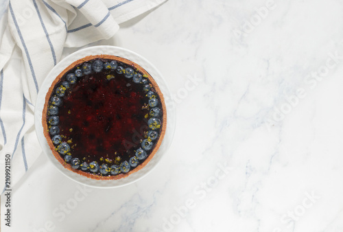 Homemade shortbread pie with blueberries in a white plate on a marble background. Top view, copy space