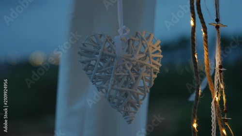 Romantic wicker heart decoration hanging outdoors at twilight