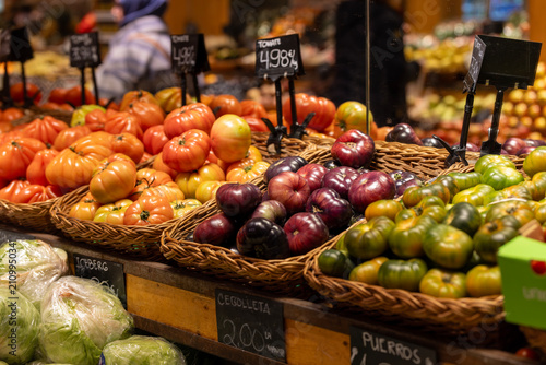 Large, vibrant beefsteak tomatoes are perfectly arranged in wicker baskets at a local market stall.