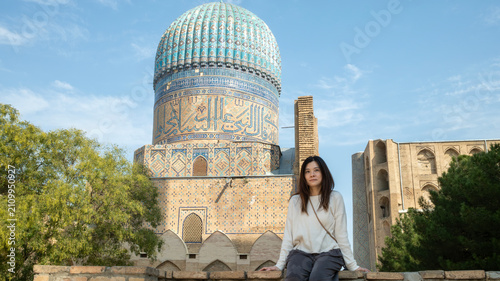 A female traveler poses in front of the magnificent turquoise dome of the historic Bibi-Khanym Mosque.