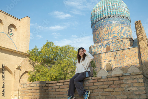 A female traveler poses in front of the magnificent turquoise dome of the historic Bibi-Khanym Mosque.