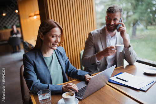 Businessman and businesswoman collaborating on a financial report and analyzing data in a coffee shop