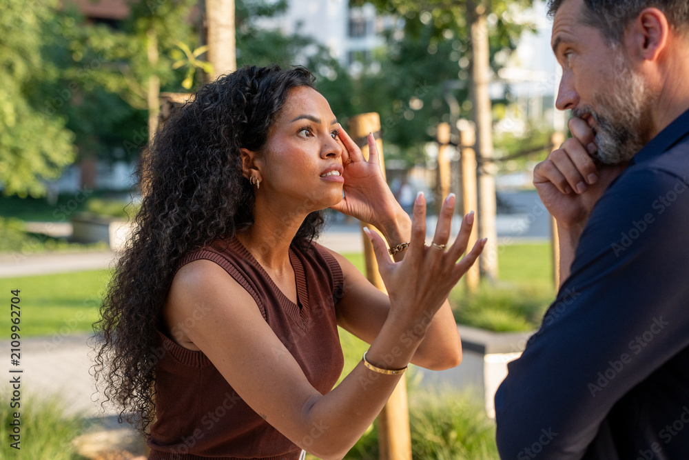 Fototapeta premium Frustrated woman arguing with uninterested man outdoors, relationship conflict and communication problems in urban environment