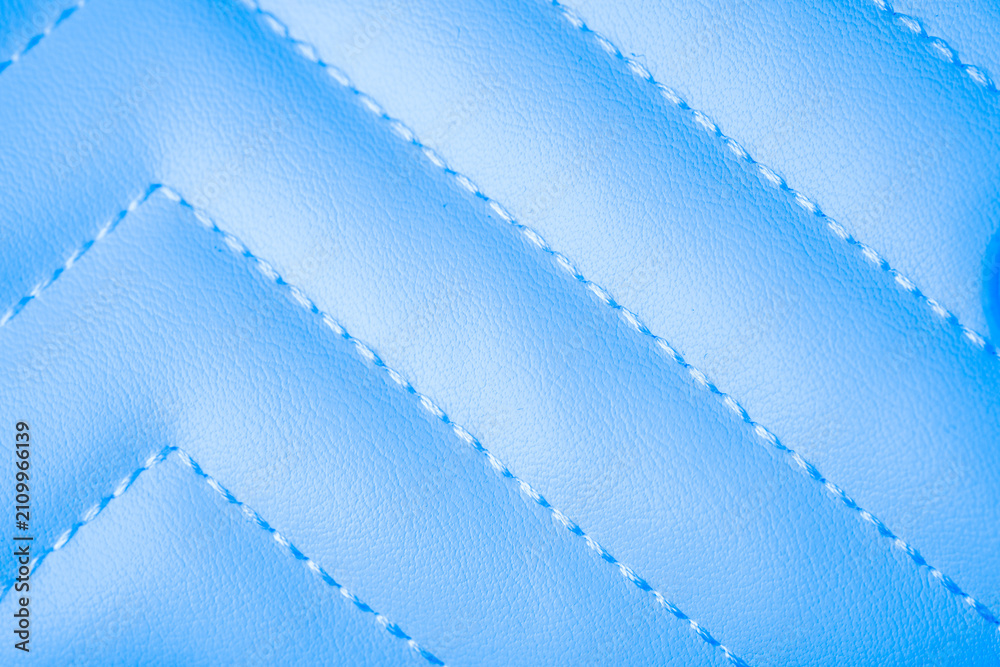 Obraz premium Elegant pastel blue quilted leatherette fabric texture background with distinct diagonal stitching design