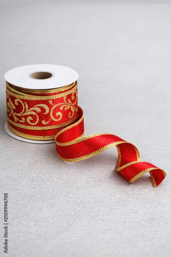 Fototapeta premium Two rolls of red and gold ribbon, possibly for gift wrapping or crafting