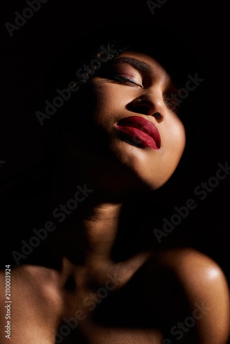 Принти на полотні Young beautiful African American woman showcases chic elegance with graceful allure in low light