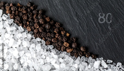Close-up of Coarse Sea Salt and Black Peppercorns on a Dark Slate Stone Background