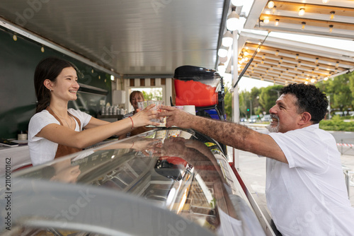 Young woman vendor serving refreshing drink to happy customer