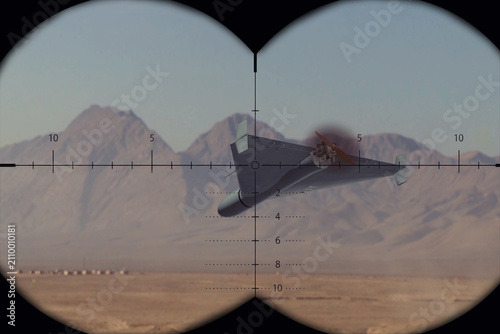фотографія Military observer tracks an attack drone through binocular targeting optics in a desert area