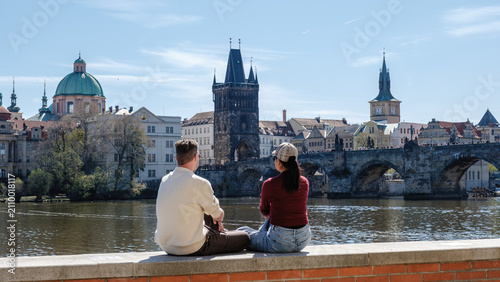 Bild auf Leinwand A couple sits peacefully by the Vltava River, admiring beautiful views of Prague