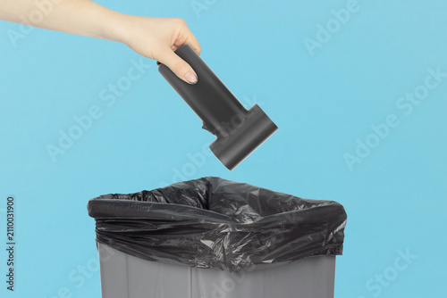 Throwing a portable electric air duster  into the trash can, holding a electric air duster in front of the trash can