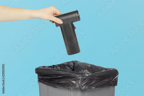 Throwing a portable electric air duster with wide nozzle attachment into the trash can, holding a electric air duster in front of the trash can