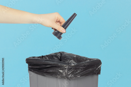 Throwing a long narrow nozzle attachment for electric air duster into the trash can, holding a long narrow nozzle attachment for electric air duster in hand front of the trash can