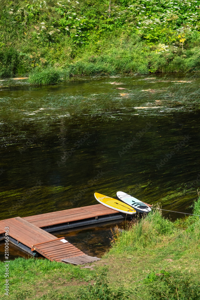 Fototapeta premium Two sapboards lying on a wooden pontoon by the river.