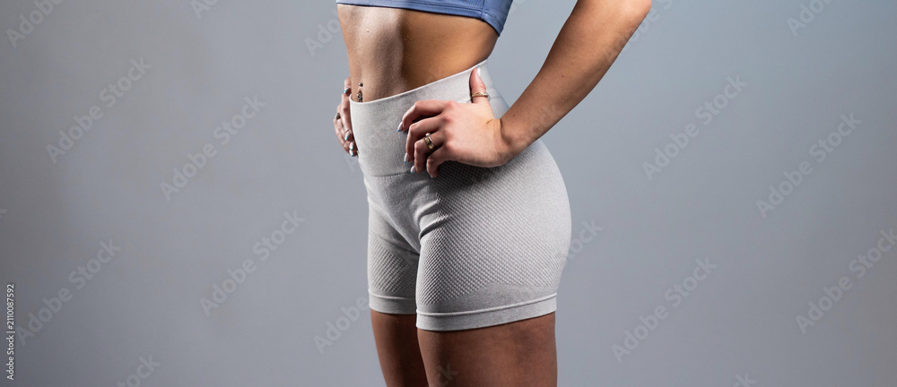 Fototapeta premium Fit woman in gray textured workout shorts posing with hands on hips