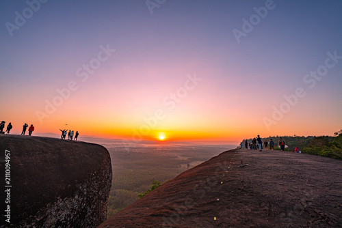Cuadro en lienzo Epic sunrise at a famous Thai viewpoint, capturing tiny human figures on a colossal rock ledge above a sea of trees, evoking adventure, scale, and serenity