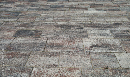 Картината върху платно Modern gray and brown paving stones with a textured surface are laid in even rows across an urban plaza