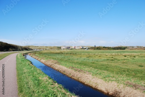 Quadro su tela Peaceful canal running through green Dutch polder meadows