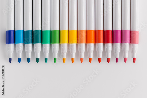 Top view of colorful felt tip pens arranged in a row gradient on white background