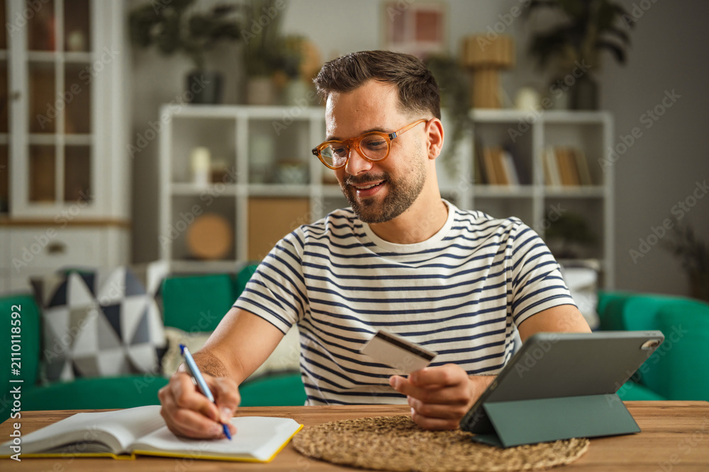 Obraz premium Man shopping online using tablet and credit card at home