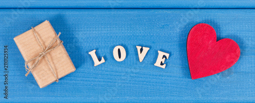 Gift with ribbon, red heart and word love as surprise for Valentines Day or other celebration