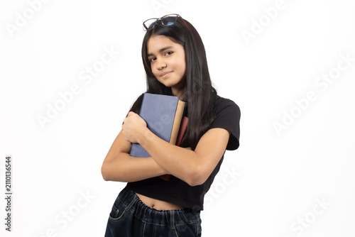 Young girl holding books looking pensive in bright studio space