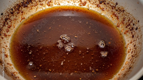 Close up of a golden caramel sauce in a metal bowl.