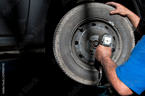 Cuadro en lienzo Mecânico realiza manutenção em roda de automóvel com chave de impacto, destacando o trabalho técnico, a manutenção preventiva e os serviços de oficina automotiva