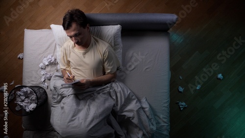 Canvastavla Young man lying in bed at night, struggling with insomnia and creative block, wr