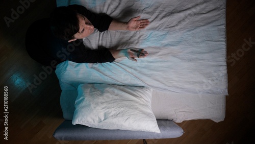 Obraz na płótnie Man lying in bed with eyes open, hands outstretched, and a focused gaze, illustr
