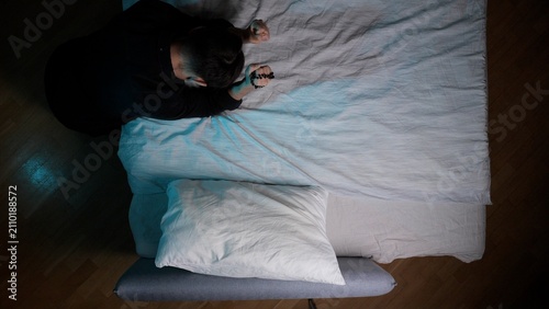 Obraz na płótnie Man kneeling beside his bed, holding a rosary in clasped hands, engaged in praye